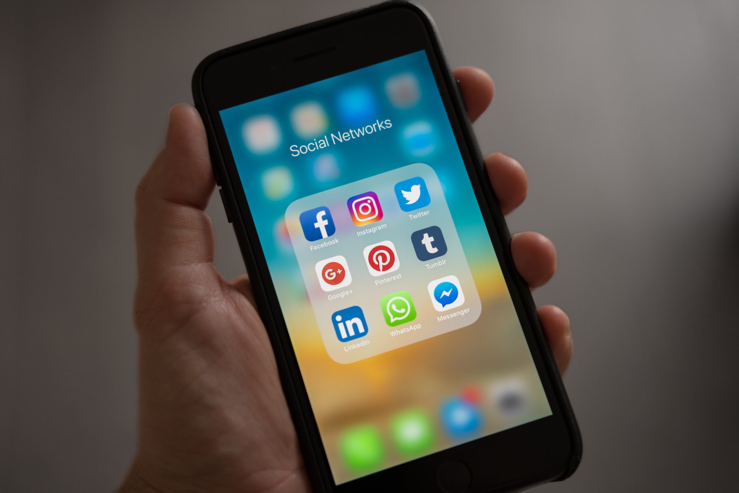 Smartphone sendo segurado por uma pessoa com a tela acesa e vários aplicativos de redes sociais como Facebook, Instagram, Twitter, Pinterest, Linkedin e WhatsApp