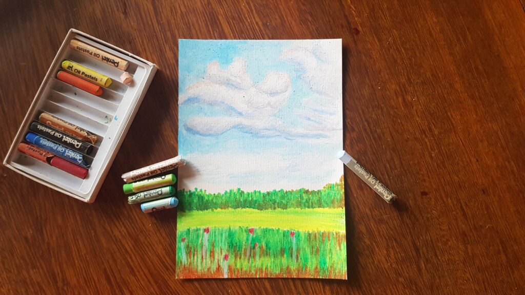 Pintura de pastel a óleo sobre papel. Uma paisagem com flores vermelhas bem pequenas, grama e um céu azul com algumas nuvens.