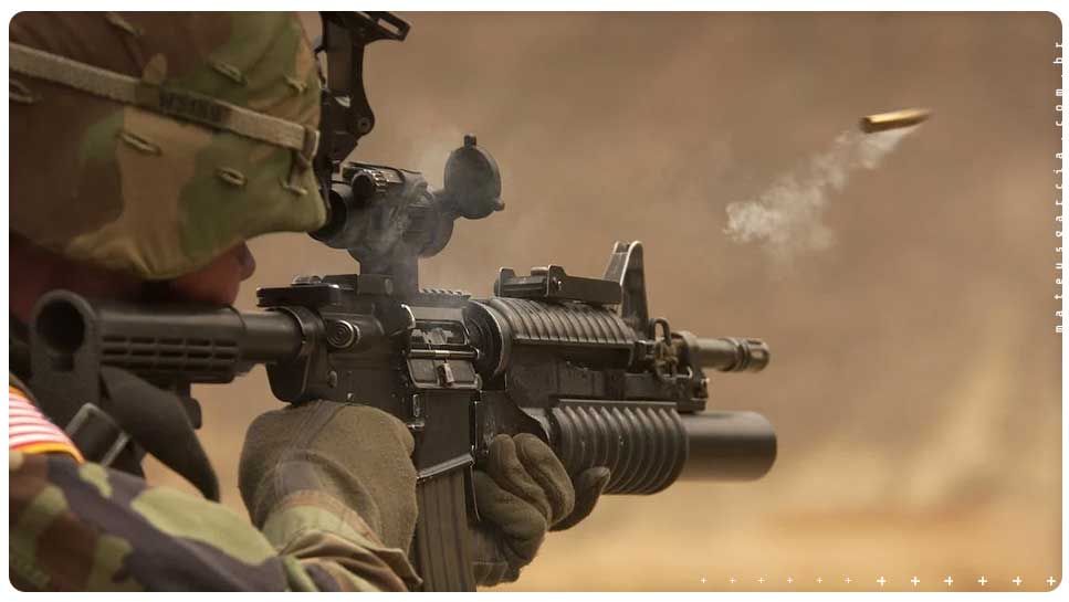 Um soldado com um rifle que acabou de disparar um tiro. A capsula do projétil ainda está saindo da arma pela lateral.